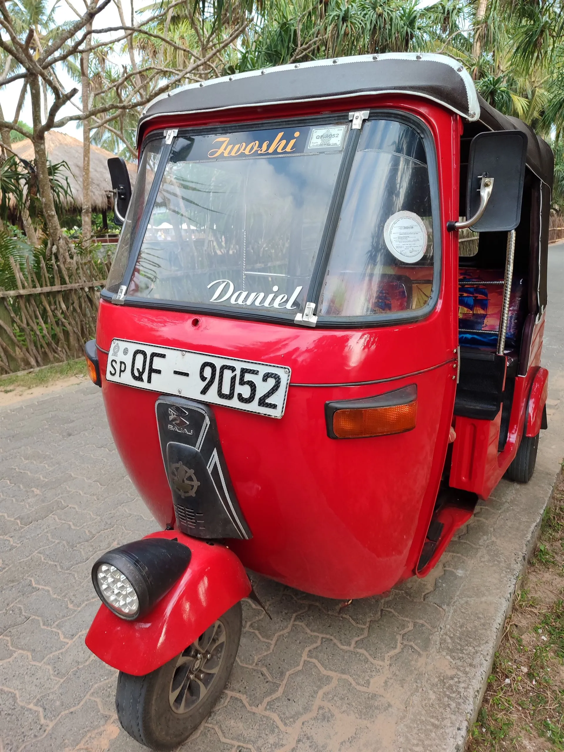 Ein rotes Tuk-Tuk mit dem Namen des Fahrers über der Windschutzscheibe