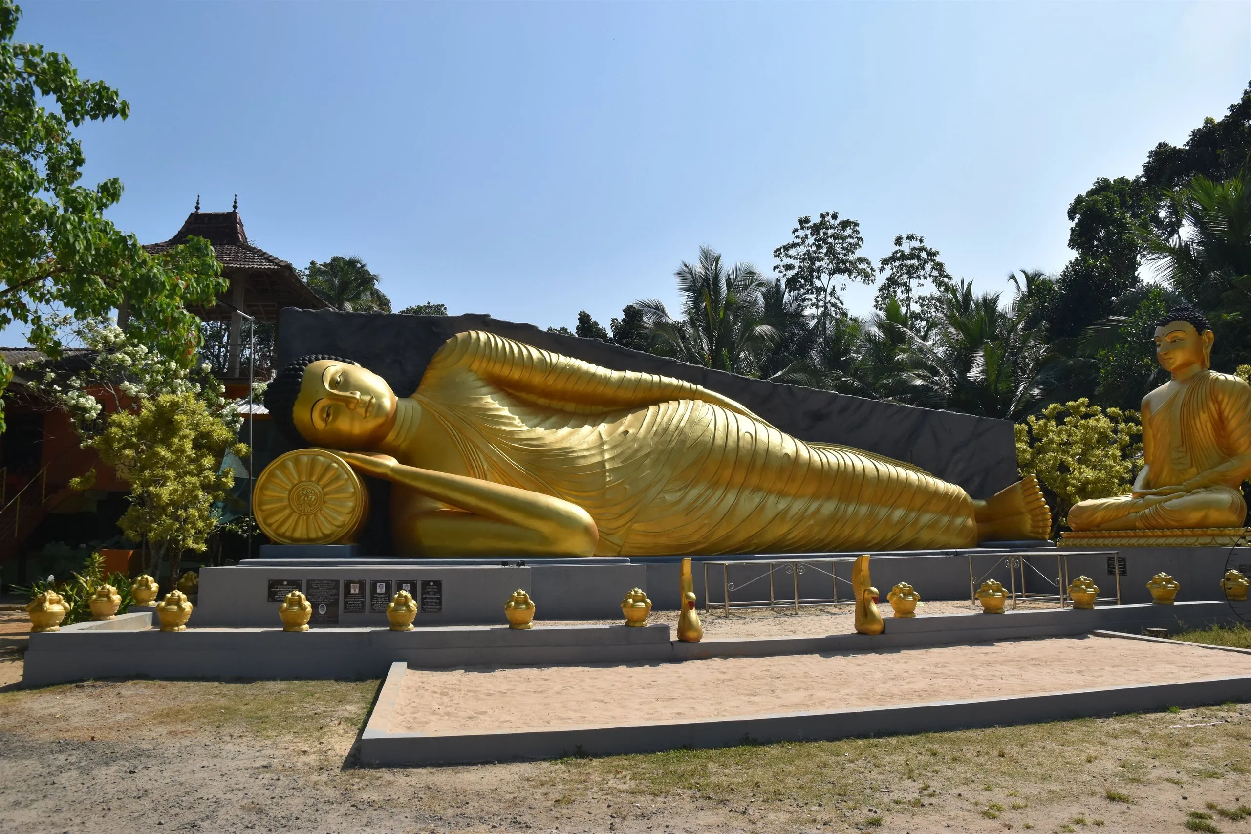 Ein großer goldener liegender Buddha im Tempelgarten
