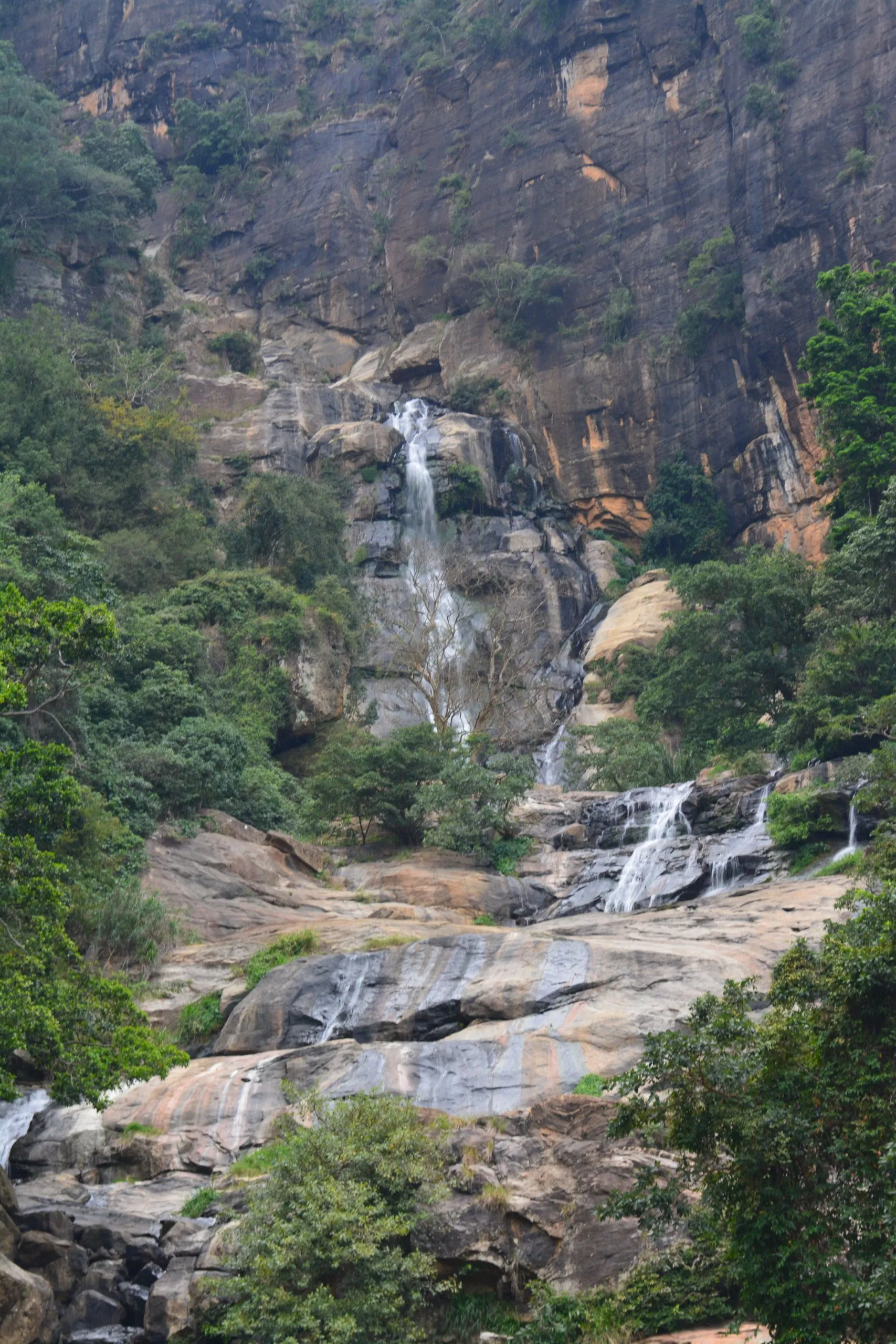 Ein hoher Wasserfall, der in Stufen eine Dschungelwand hinabfällt