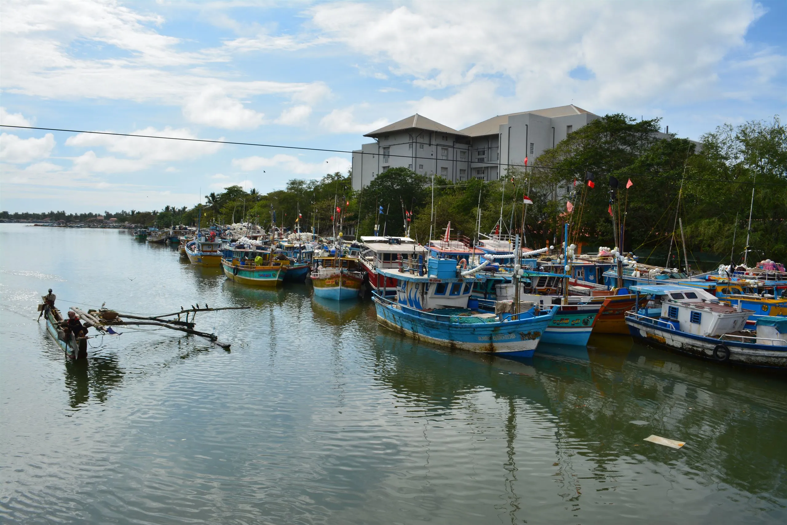 Fischerboote in der Lagune von Negombo, ein Auslegerkanu fährt hinaus