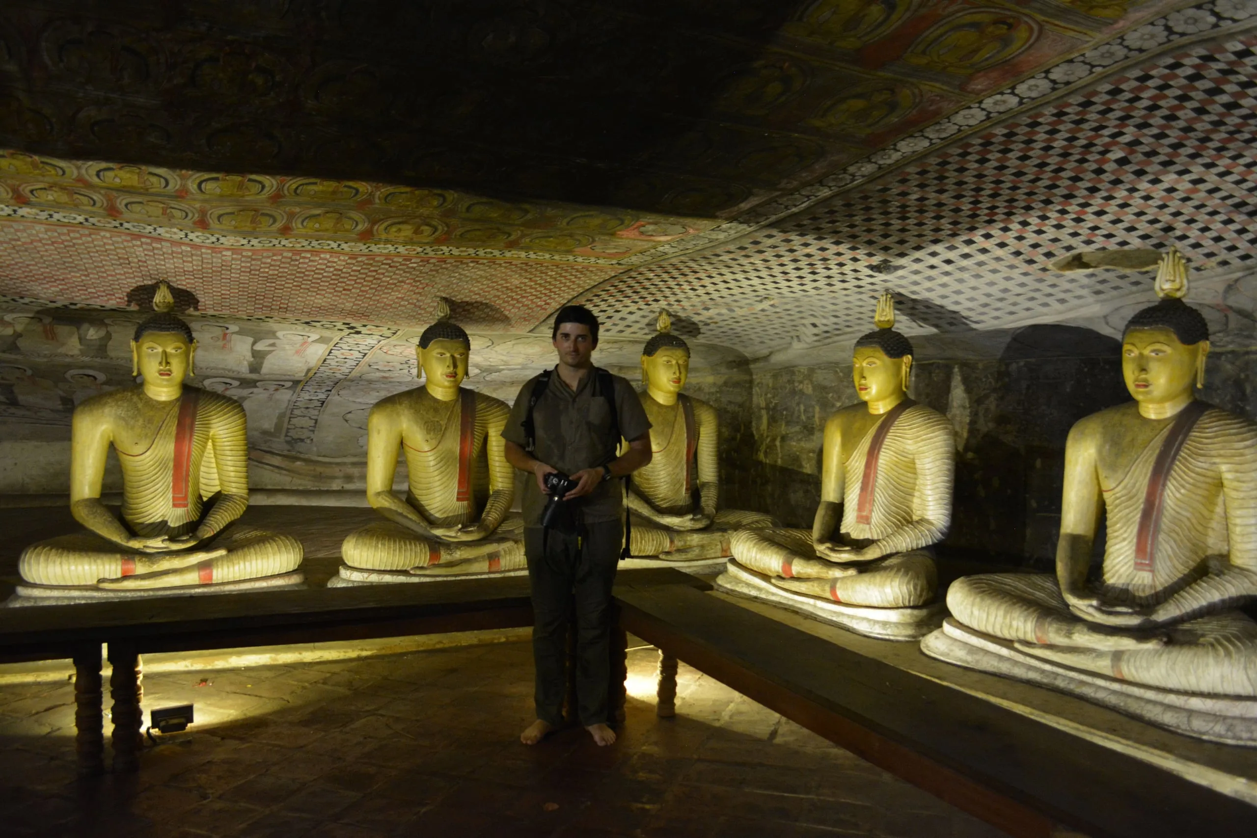 Buddha-Statuen und eine bemalte Decke in einem Felsenhöhlentempel