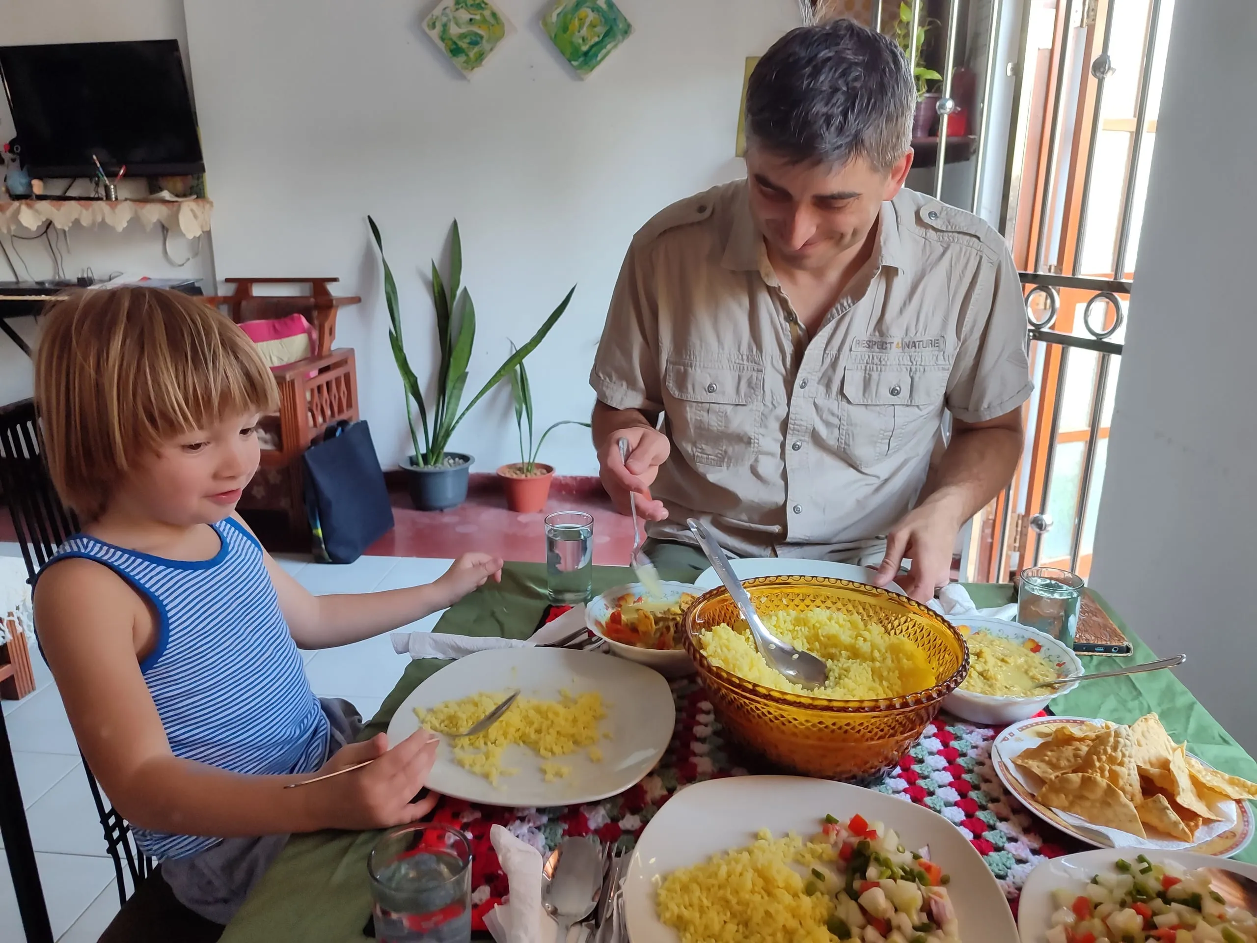 Ein Mann und ein kleiner Junge an einem Familientisch mit gelbem Reis, Currys und Papadams