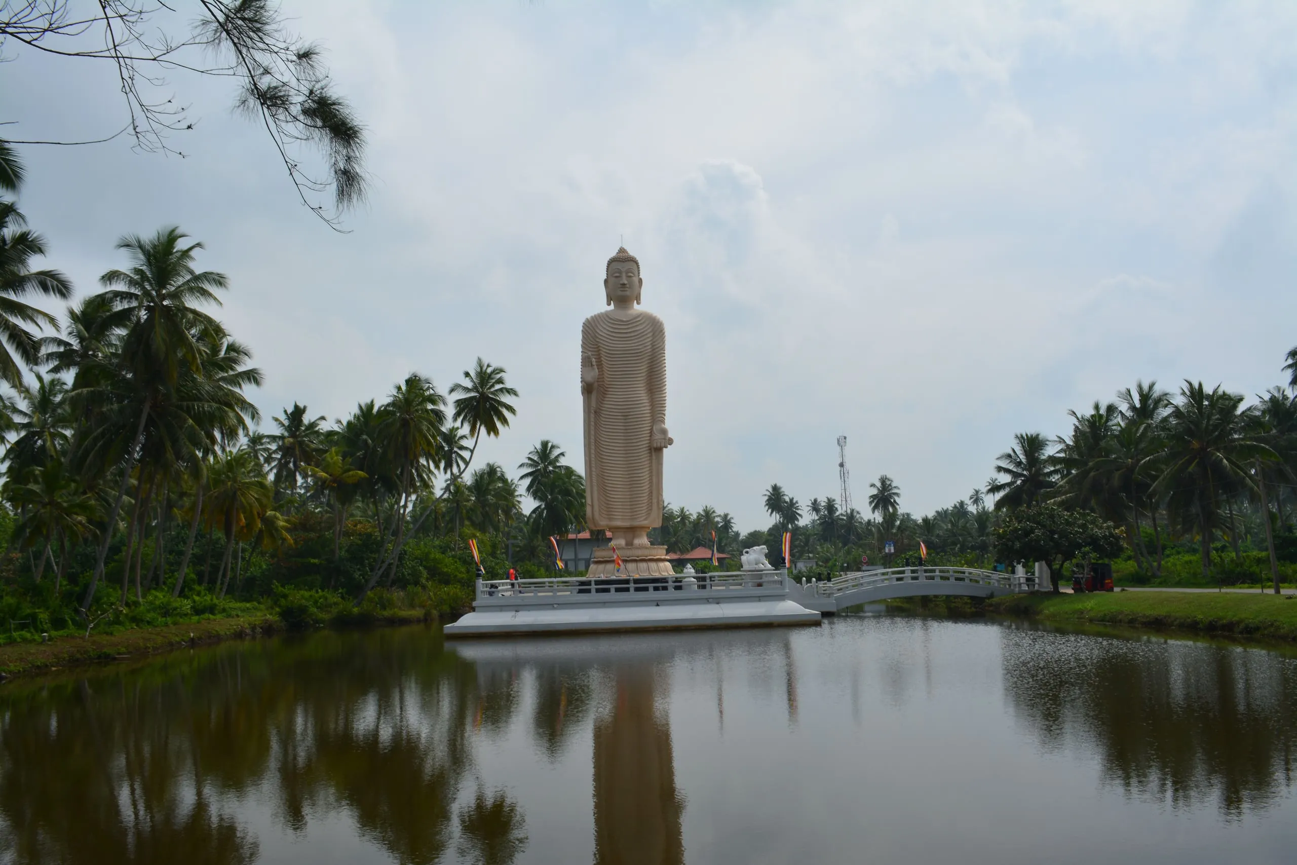 Vysoký stojící Buddha památníku tsunami v Peraliyi, odražený v laguně