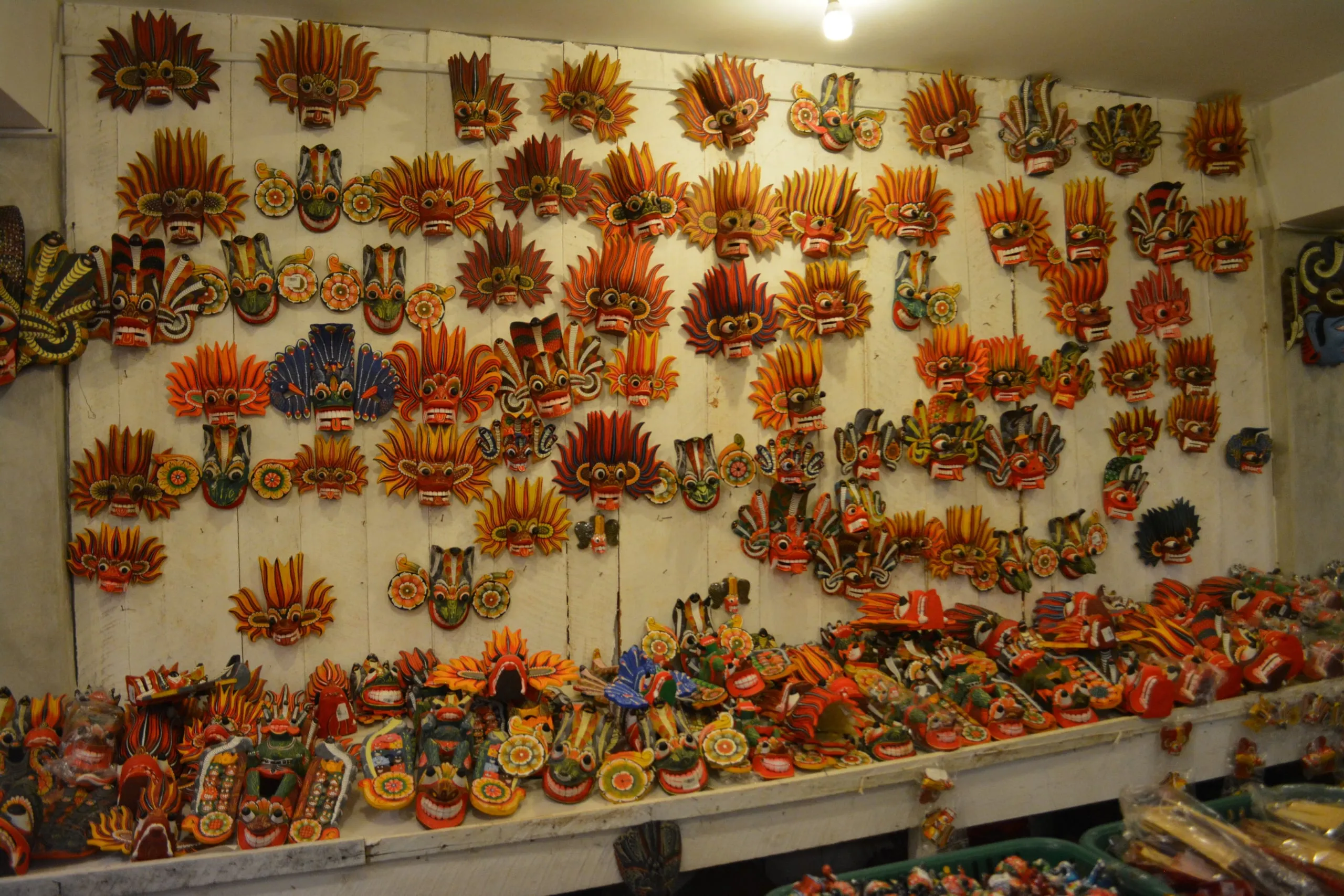 Eine Wand voller handgeschnitzter und bemalter Masken in einer Schnitzwerkstatt